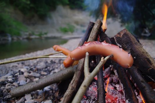 a sausage grilled on a camp fire