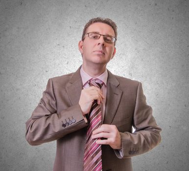 Portrait of thoughtful young businessman putting his stripes tie, isolated on white background