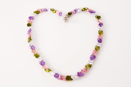 necklace of colored stones  in the shape of heart on a light background