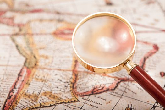 A beautiful antique map with an old magnifying glass with golden details.