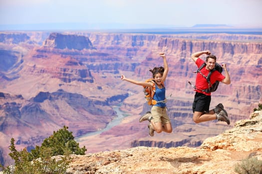 Happy people jumping in Grand Canyon. Young multiethnic couple on hiking travel. Grand Canyon, south rim, Arizona, USA.