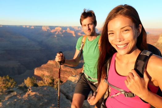 Couple hikers in Grand Canyon. Aspirational lifestyle image of happy young people hiking the South Rim trail of Grand Canyon. Multiethnic couple, Asian woman, Caucasian man.