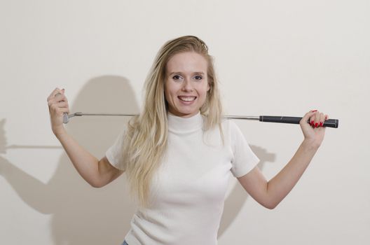 blonde girl holding golf club on her shoulders smiling