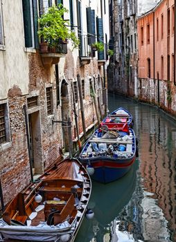 Motorboats parked near specific walls of houses on a small canal in Venice
