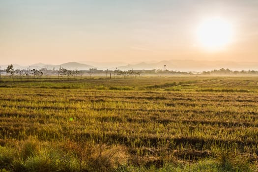 Sunrise behind the mountains in grass field and fog early morning time