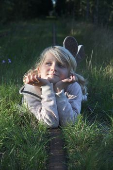 An 8 year old lying on an abandoned rail road track in the forest, daydreaming. Positive feeling