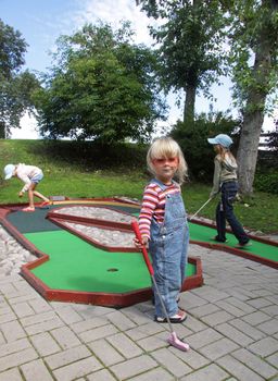 Three kids on a miniature golf course