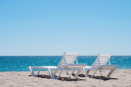 Two chaise longues on the beach, blue sky