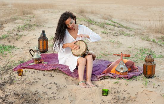 Woman playing a traditional djembe in a desert setting