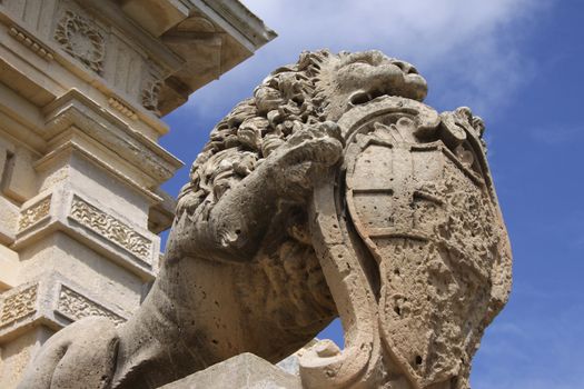 Closeup of an old statue of a lion holding a coat of arms