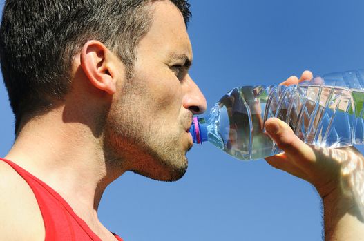 Man is drinking water against blue sky