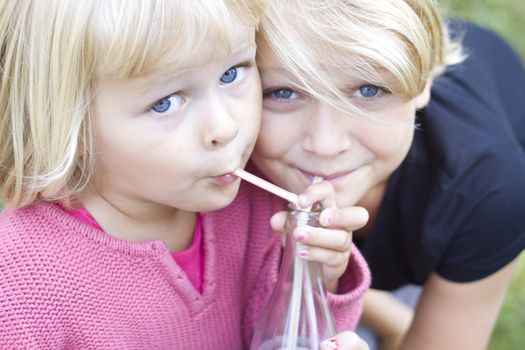 Children sharing bottle with straws