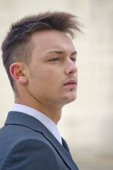 Profile portrait of attractive young businessman in suit