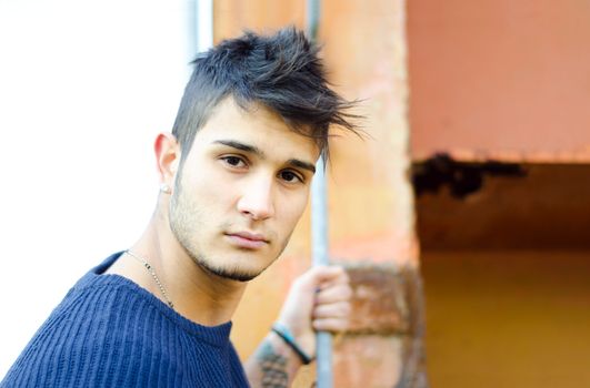 Handsome young man in urban or industrial setting with rusty metal structure