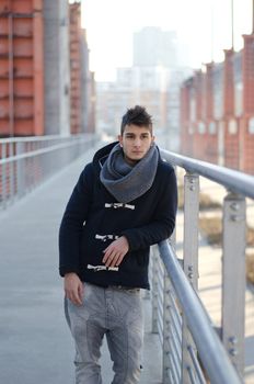 Handsome young man standing in urban or industrial setting, winter clothes