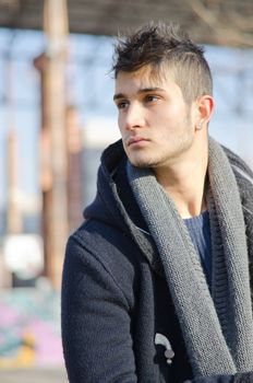 Handsome young man in urban or industrial setting, looking to a side