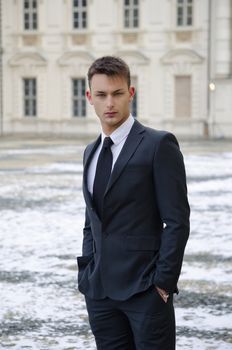 Good looking young man in suit, elegant palace with snow on the ground