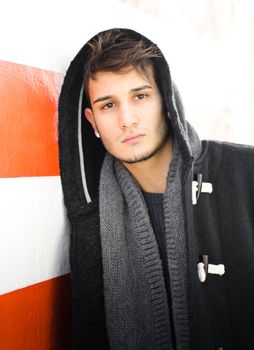 Good looking young man in hoodie against white and orange striped wall