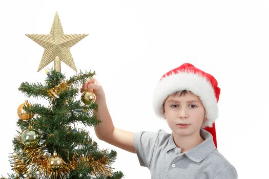 Boy with santa hat decorates the Christmas tree on white background