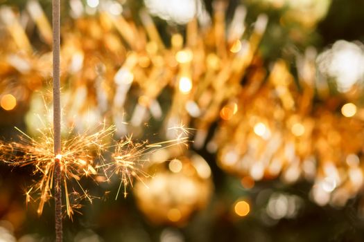 burning sparkler and out of focus christmas tree 