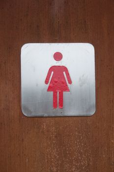 woman symbol in front of toilet wooden door