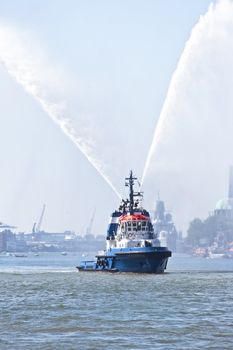Blue fire boat on  harbor  spraying bright streams of water in demonstration in Rotterdam the Netherlands