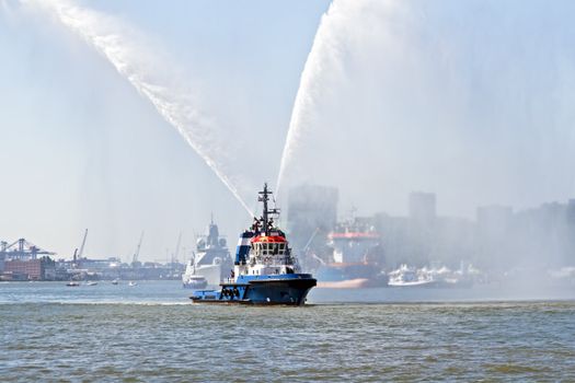 Blue fire boat on  harbor  spraying bright streams of water in demonstration in Rotterdam the Netherlands