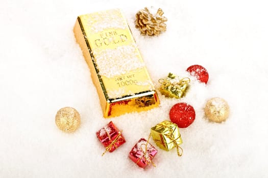 Golden bar as christmas present in the snow with ornaments