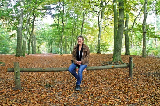 Mature woman sitting on a bench in the woods