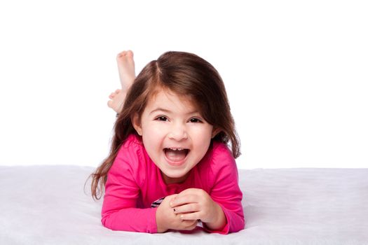 Cute happy laughing toddler child girl laying on belly supporting on elbows, on white.