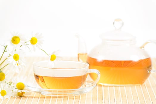 A teacup and a teapot with herbal chamomile tea