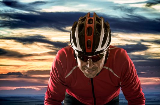 Cyclist with helmet against cloudy sunset sky.