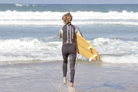 Young surfer is going to surf in the atlantic ocean