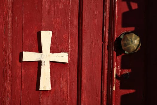 cross on a red wooden door closeup