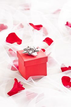 Red Gift box with silver bow on wedding veil with rose petals