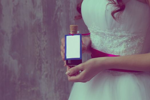 girl in a white dress holding a bottle labeled