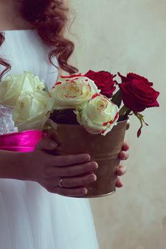 girl in a white dress holding a bucket of roses