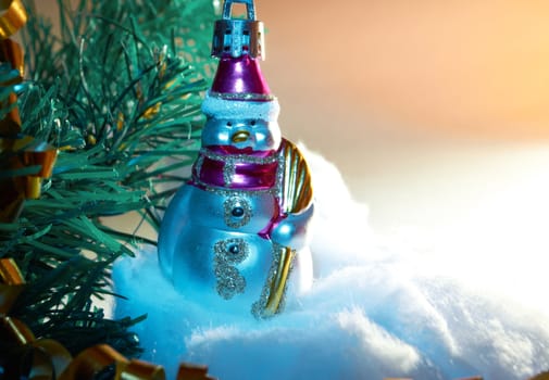 Glass Christmas toy  in the form of snowman on the artificial Christmas tree branches 