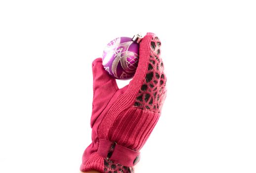 Hand in the women's pink glove holding a Christmas ball