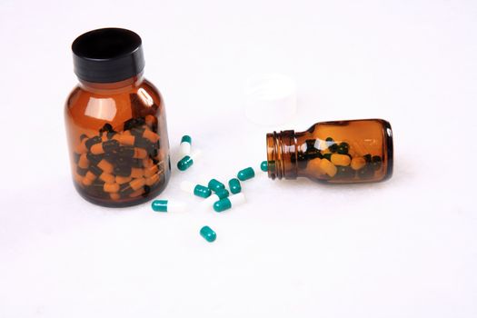 medicine pills pouring out of orange bottle on a white marble. selective focus