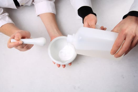 hands mixing ingredients on mortar with pestle