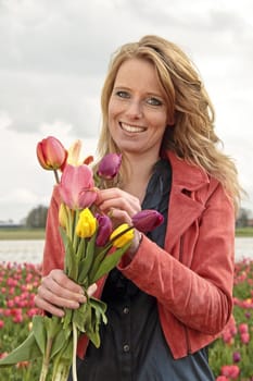 Beautiful woman with tulips in the tulip fields in the Netherlands