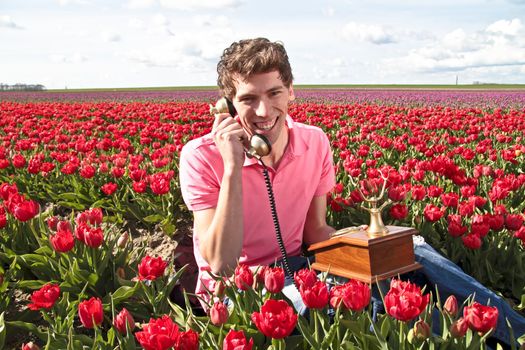 Young happy guy making a phone call in the tulip fields