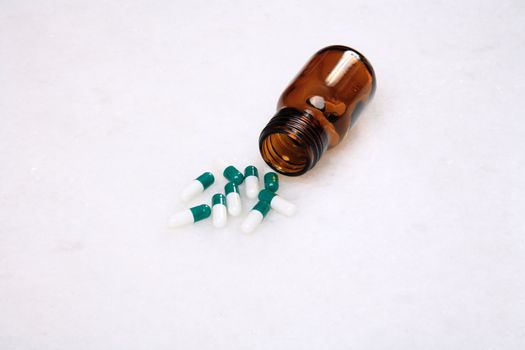 medicine pills pouring out of orange bottle on a white marble. selective focus