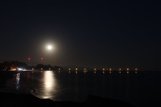 Full Moon over the Goleta Pier with reflection on the ocean.