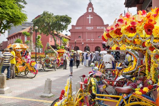 MELAKA, MALAYSIA - JAN 14 : Christ Church Melaka on Jan 14, 2012 in Melaka Malaysia. A popular historic tourist attraction in Melaka Malaysia with flower decorated tricycles for hire.