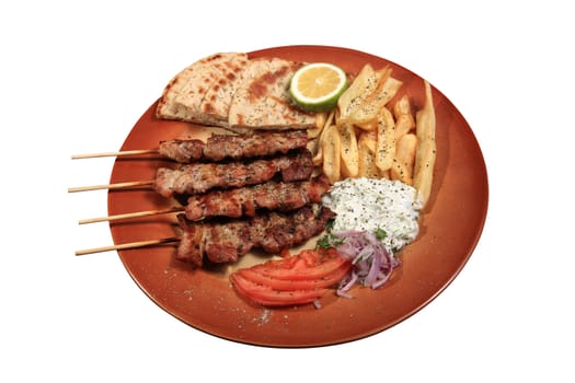 pork skewers served on a plate with fries tzatziki pita and tomato in a greek style