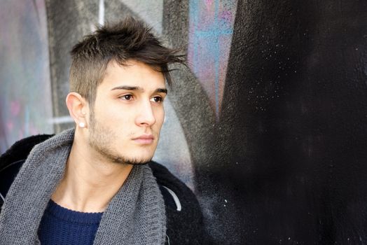 Attractive young man looking to a side against colored wall, large copy-space