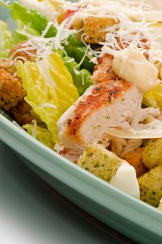 Caesar Salad with Grilled Chicken, Crouton, Romaine Lettuce,  Sauce and Grated Parmesan Cheese closeup on Green Plate