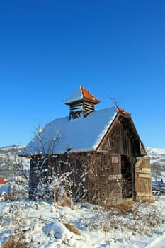 A lonely wooden barn in the winter meadow